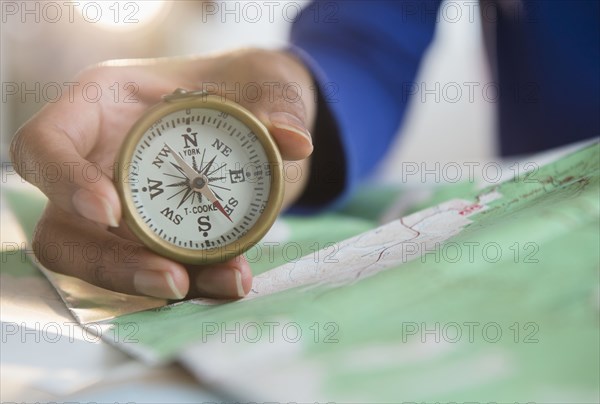 Mixed race woman holding map and compass