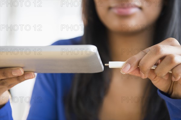 Mixed race woman plugging in digital tablet