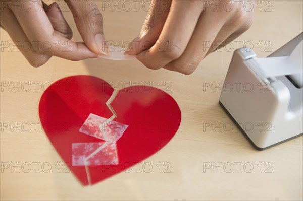 Mixed race woman taking broken paper heart