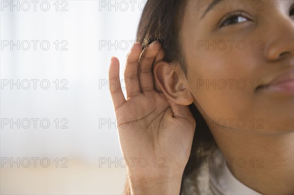 Mixed race woman cupping her ear