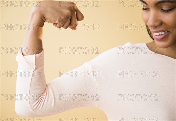 Mixed race woman flexing her muscles