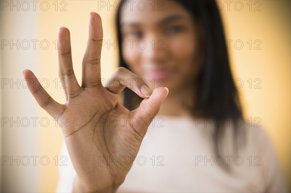 Mixed race woman making OK symbol