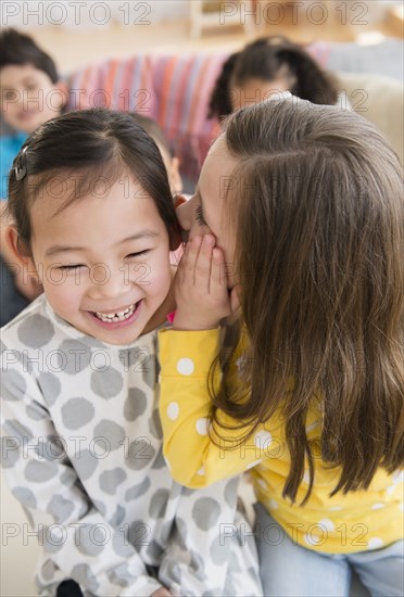 Girl whispering into friend's ear
