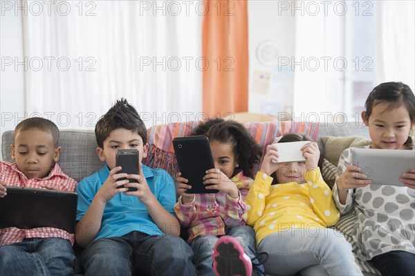 Children using technology on sofa