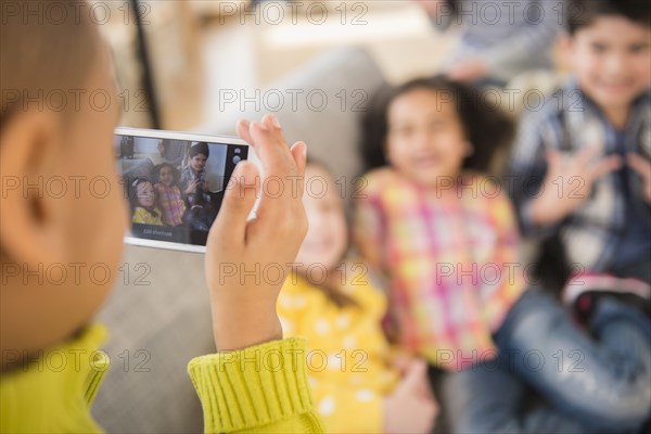 Boy photographing friends on sofa