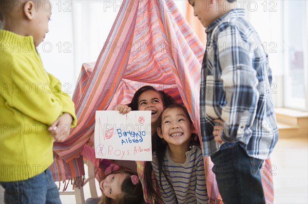 Girls holding No boys Allowed sign in living room