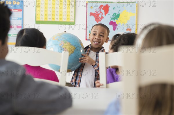 Boy showing globe to classroom