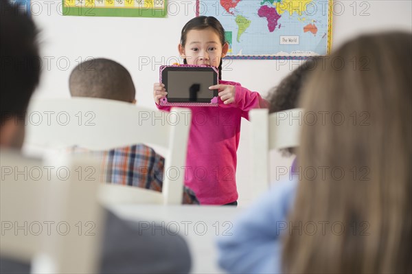 Girl showing digital tablet to classroom