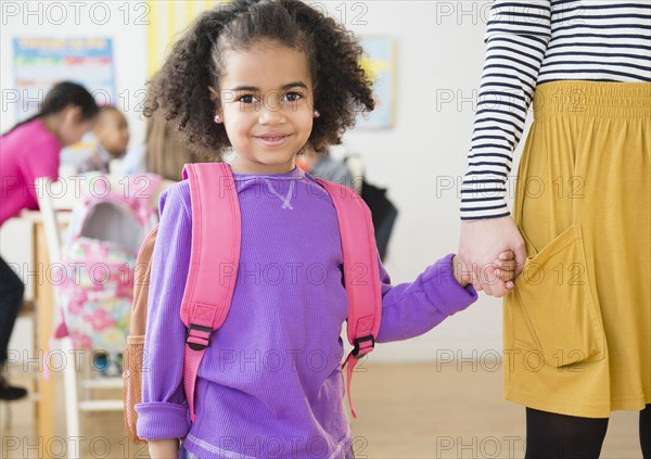 Student and teacher holding hands in classroom