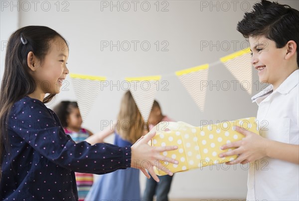 Boy giving girl birthday present at party