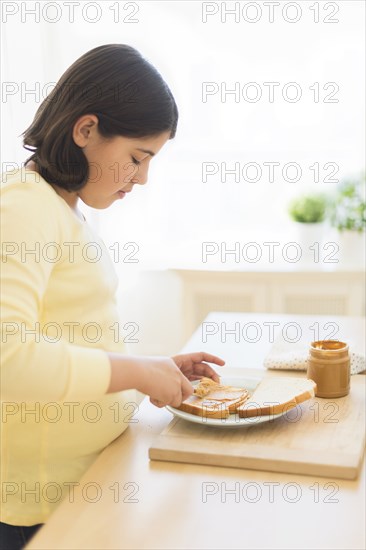 Hispanic girl making peanut butter sandwich