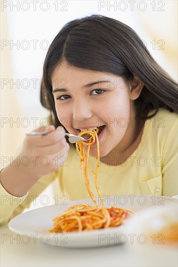 Hispanic girl eating plate of pasta