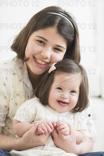 Hispanic girl holding toddler sister in living room