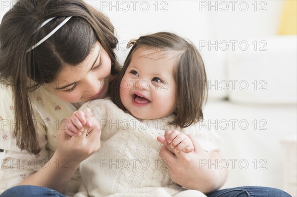 Hispanic girl holding toddler sister in living room