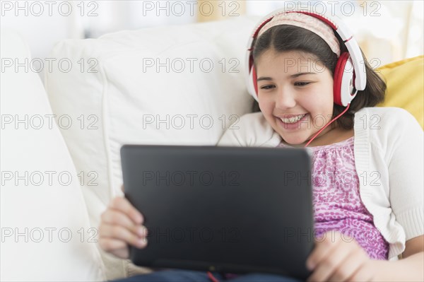 Hispanic girl using digital tablet on sofa