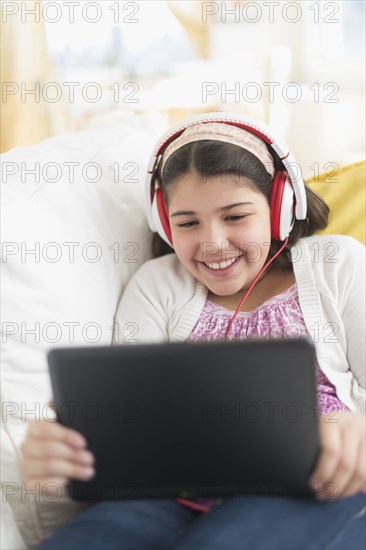 Hispanic girl using digital tablet on sofa