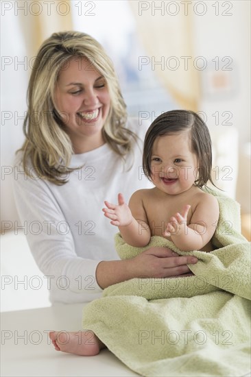 Hispanic mother drying toddler daughter after bath