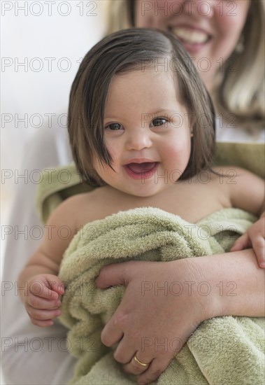 Hispanic mother drying toddler daughter after bath