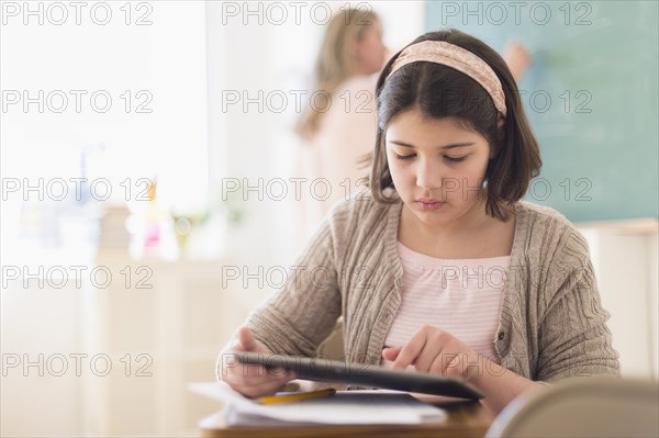 Hispanic girl using digital tablet in classroom