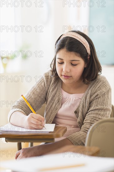 Hispanic girl taking notes in classroom