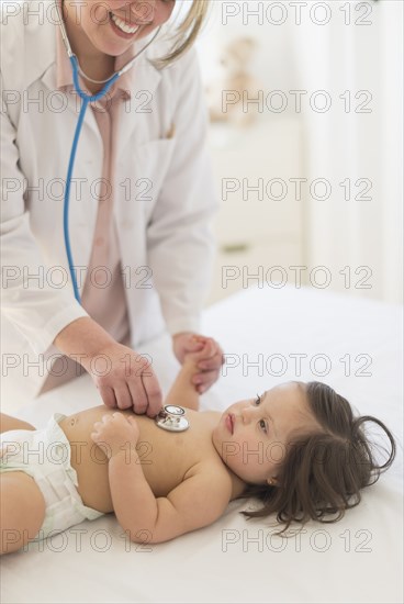 Hispanic doctor listening to toddler's heartbeat