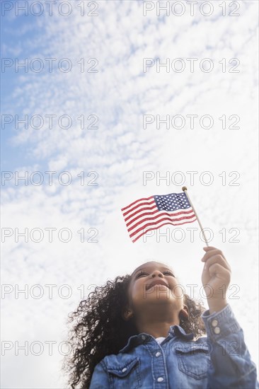 Mixed race girl holding United States flag outdoors