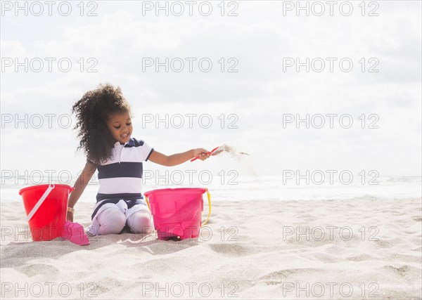 Mixed race girl playing in sand on beach