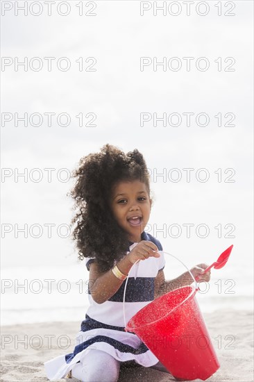 Mixed race girl playing in sand on beach