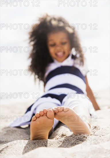 Mixed race girl playing in sand on beach