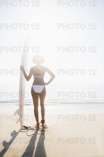 Woman holding surfboard on beach