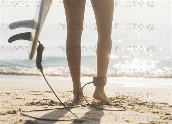 Woman tethered to surfboard on beach