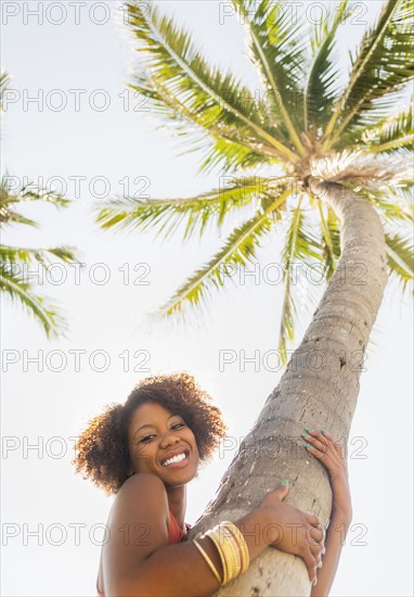 Woman hugging palm tree outdoors