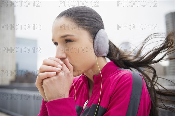 Caucasian woman warming hands in city