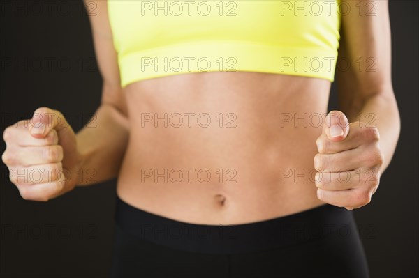 Caucasian woman with bare stomach clenching her fists