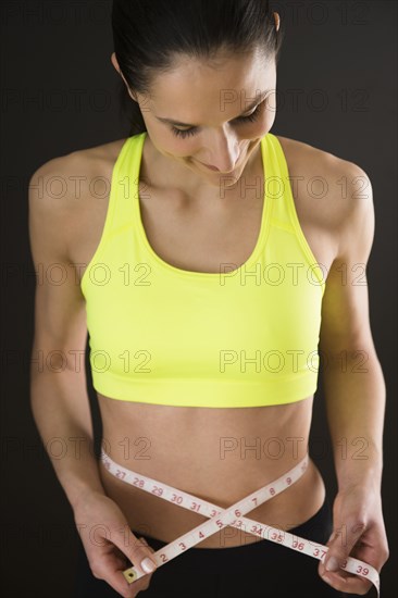 Caucasian woman measuring bare stomach