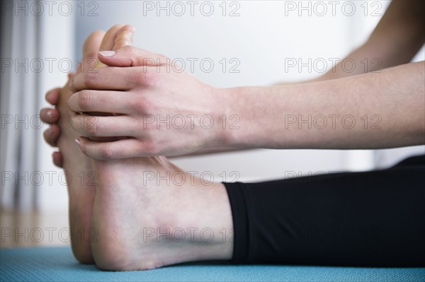 Caucasian woman stretching legs on yoga mat