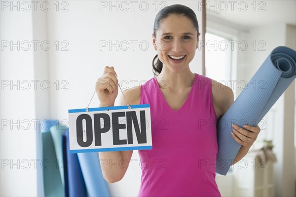 Caucasian woman holding open sign in yoga studio