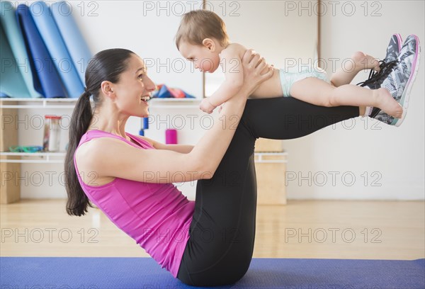 Caucasian woman holding baby on yoga mat