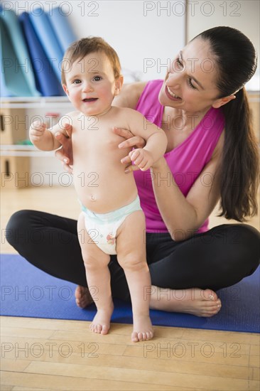 Caucasian woman holding baby on yoga mat