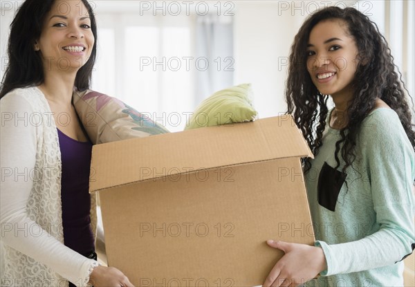 Mother and daughter carrying cardboard box