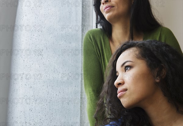 Mother and daughter daydreaming at window