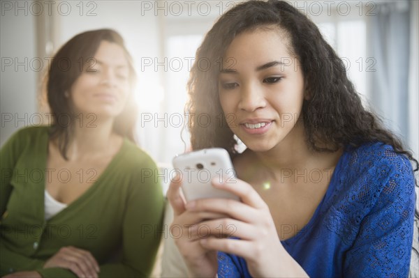 Mother watching daughter use cell phone