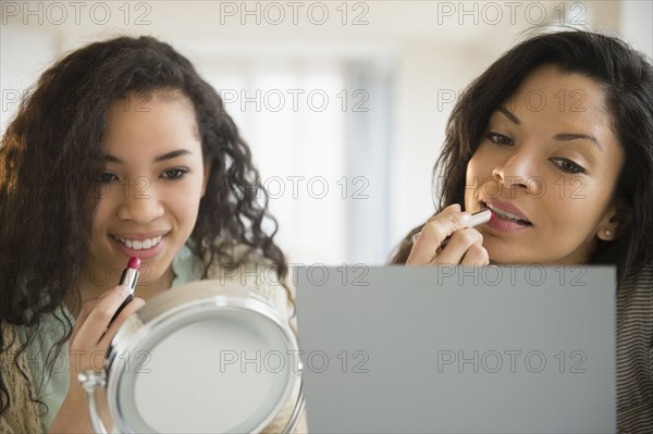 Mother and daughter applying makeup