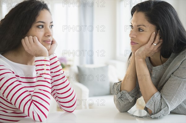 Mother and daughter with heads in hands at table