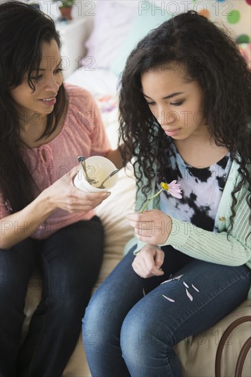 Mother comforting lovesick daughter with ice cream