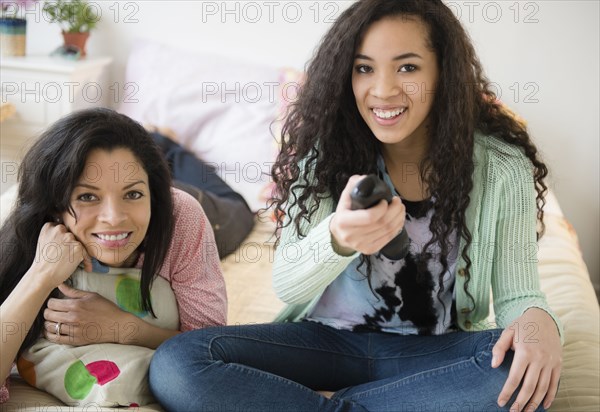 Mother and daughter watching television on bed