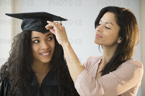 Mother adjusting teenage daughter's graduation cap