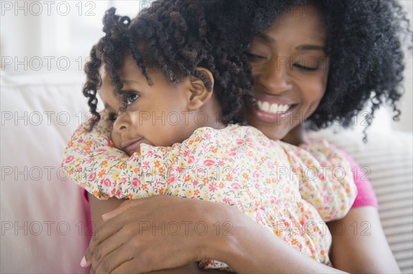 Mother hugging daughter on sofa