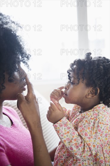 Mother and daughter touching noses on sofa