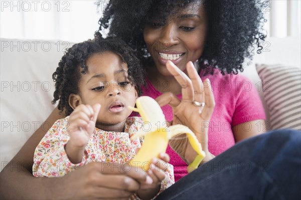 Mother and daughter eating banana